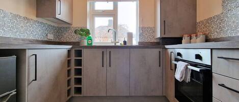 A modern kitchen with a central island, stainless steel appliances, and patterned backsplash.
