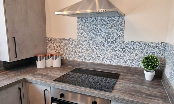 Una cocina moderna con estufa integrada, gabinetes de acero inoxidable y azulejos de salpicadero con diseño.