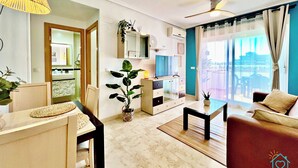 Uma sala de estar moderna com sofá, mesa de jantar e área de cozinha com televisão.