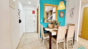 Uma área de refeições com uma parede destaque azul-turquesa, uma mesa de madeira e cadeiras. Há um lustre pendurado sobre a mesa.