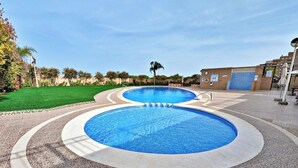 Piscina com deck revestido em azulejo e área gramada.
