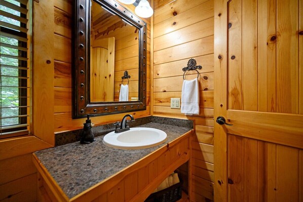 A wooden cabin bathroom with a sink, mirror, and towel rack.