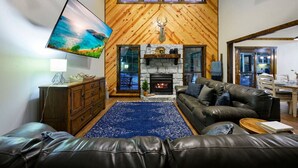 A cozy living room with a fireplace, leather sofa, and a television. - Wild Oasis · New! Wild Oasis: Pool, Gameroom, Theatre, Hot Tub (Broken Bow)