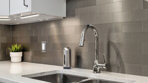 Una cocina moderna con dos lavamanos de acero inoxidable, un grifo elegante y una planta en maceta sobre la encimera.
