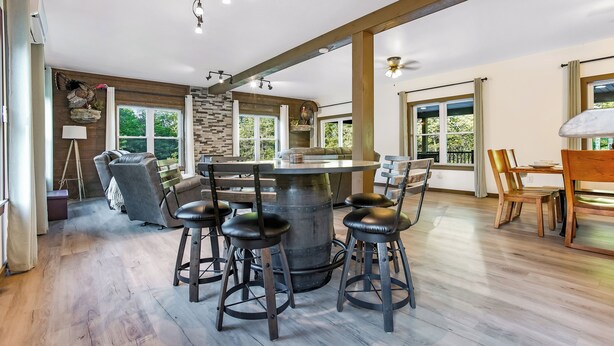 Una cocina amplia con una isla central, taburetes de bar y un comedor con sillas de madera.