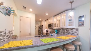 A kitchen with a curved island, stainless steel appliances, and a tiled backsplash. - 4Ever Paradise-New Listing-End Unit/2nd Floor-Near Conf Center! (Panama City Beach)