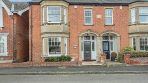 A two-story brick house with bay windows, a front door, and a small front garden.