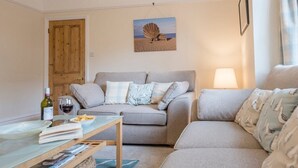 A cozy living room with a grey sofa, a wooden coffee table, and a lamp.