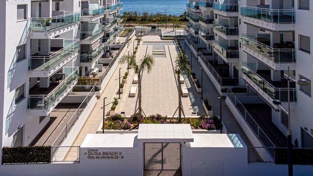 Ein modernes Apartmenthaus mit Balkonen, einem Innenhof und Blick auf das Meer.