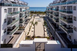 A modern apartment building with balconies, a central courtyard, and a view of the sea. - Duna Beach 2, 3 bedroom (Torrox)