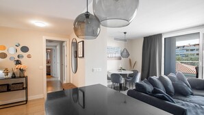 Ein modernes Wohnzimmer mit einem großen schwarzen Tisch, grauen Sofas und Pendelleuchten.