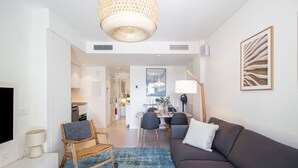 A modern living room with a sofa, a coffee table, a dining area with chairs, and a kitchen in the background. - Marinsa Beach Phase 2, 1 bedroom (Torrox)