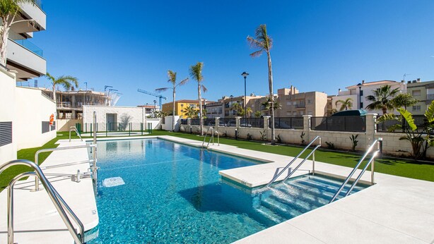 A swimming pool with clear blue water, surrounded by a white deck and metal railings. - Marinsa Beach Phase 2, 1 bedroom (Torrox)
