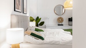 A neatly arranged bedroom with a bed, a bedside lamp, a wall-mounted mirror, and a hanging light fixture. - Marinsa Beach Phase 2, 1 bedroom (Torrox)