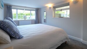 A bedroom with a large bed, two windows, and wall-mounted lights.