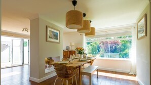 A dining area with a wooden table, wicker chairs, and pendant lights.
