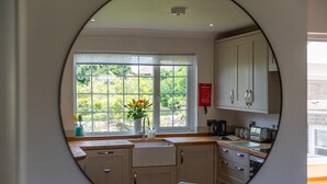 A kitchen with a view of greenery through a window, a sink, cabinets, and a breakfast setup on the counter.