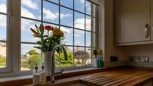 A kitchen with a window, wooden countertop, and a sink with a faucet.