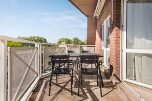 Enjoy the view from this balcony with a table and two chairs.