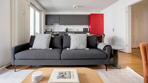 A modern living room with a grey sofa, a small table with a magazine, and a red cabinet in the background. - Clean Klybeck 3BR w/ Elevator & W/D, near River, by Blueground (Basel)