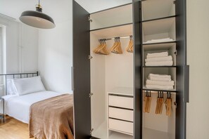 Une chambre à coucher comprenant un lit, une armoire avec espace pour suspendre les vêtements et une table de chevet.