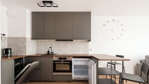 Cocina compacta con electrodomésticos integrados, horno empotrado y un pequeño comedor con mesa y sillas.