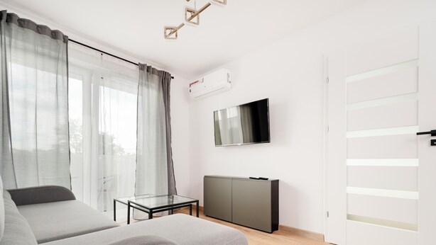 Un dormitorio moderno con cama, televisor y armario.