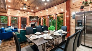 A modern log cabin with a dining area, kitchen, and seating.
