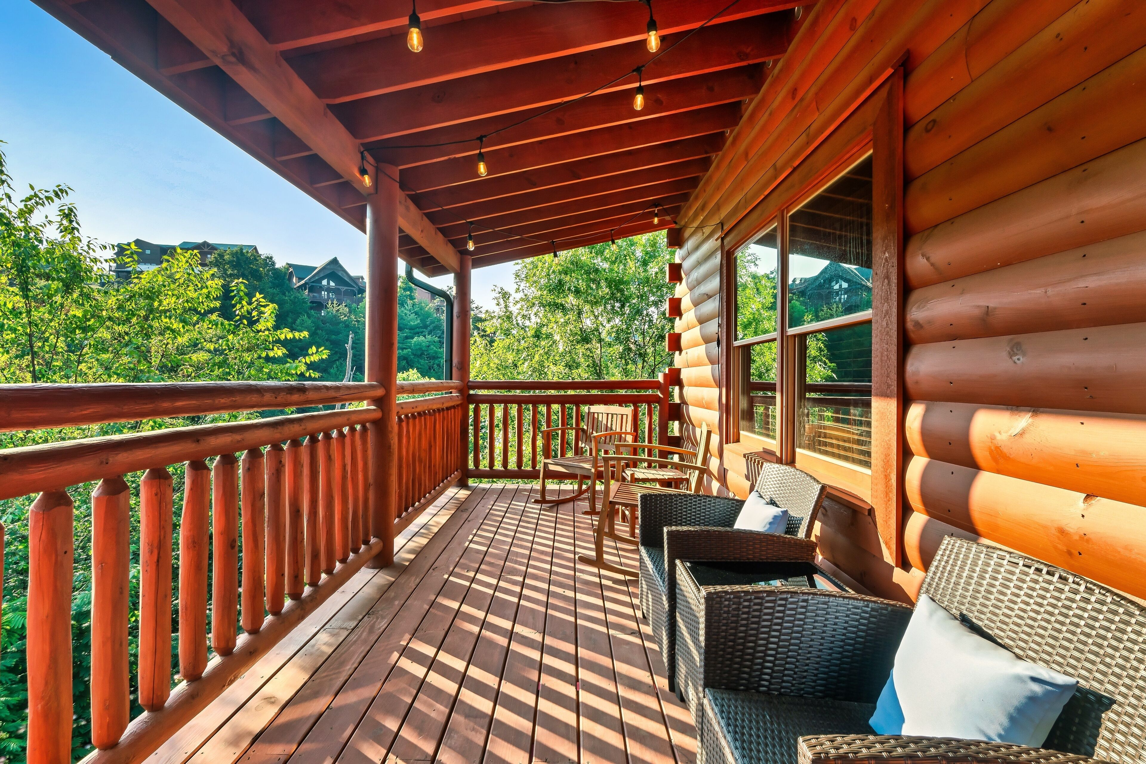 Eine Holzterrasse mit Korbmöbeln und Blick auf ein bewaldetes Gebiet.