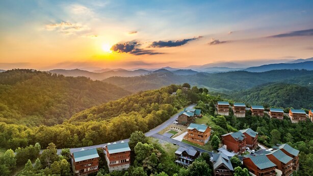 A resort with multiple buildings, a winding road, and a mountainous backdrop.