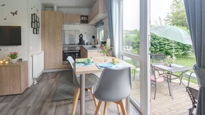 A modern kitchen with wooden cabinets, a built-in oven, and a dining area with a table and chairs. - Tiny Haus Anita by Interhome (Beilngries)