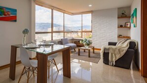 Una sala de estar moderna con comedor, ventanas amplias y vista a la ciudad.