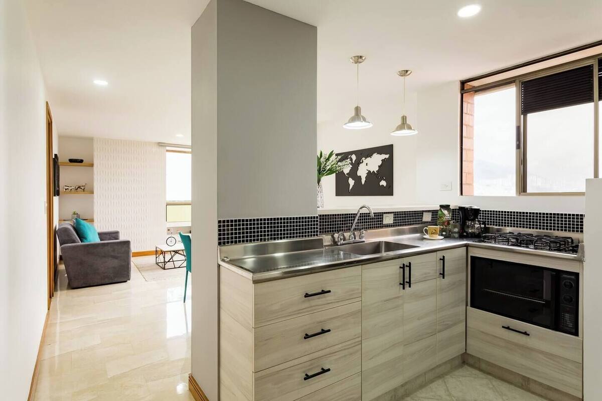 A modern kitchen with a large island, stainless steel appliances, and a black and white backsplash.