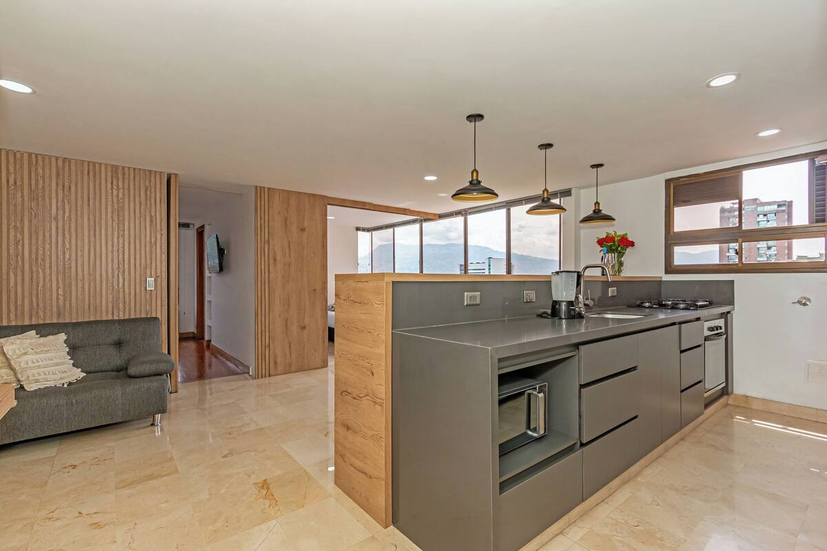 A modern kitchen with a central island, stainless steel appliances, and pendant lighting.