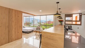 Una cocina moderna con una isla grande, un comedor con vistas, y un dormitorio con cama y una silla.