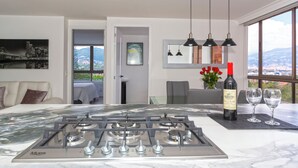 Una cocina moderna con estufa a gas, una botella de vino y vasos sobre una encimera de mármol.