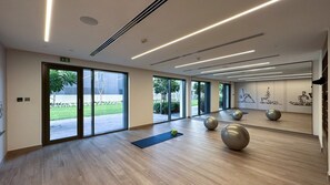 A spacious room with large windows, exercise balls, and a yoga mat.