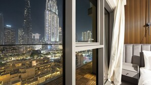 Ein modernes Hotelzimmer mit Stadtblick, einem Balkon mit Holzboden und einem Bett mit weißem Kopfteil.