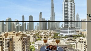 Ein Balkon mit Tisch für zwei Personen mit Blick auf eine Skyline mit modernen Wolkenkratzern.