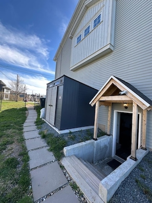 A residential building with a covered porch, a garage, and a pathway leading to the entrance.
