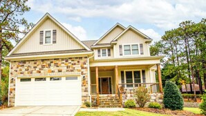 A two-story house with a stone facade, a front porch, and a garage. - Epic 13 Bed Golf Vacation - Chipping Inn (Pinehurst)