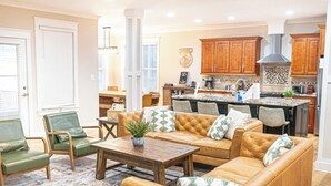 A spacious living room with a large sofa set, a coffee table, and a dining area. - Epic 13 Bed Golf Vacation - Chipping Inn (Pinehurst)