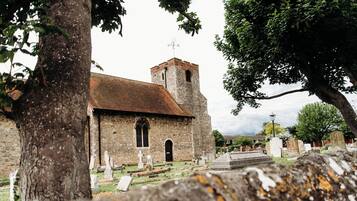 Une église dotée d’un clocher, entourée d’arbres et de pierres tombales.