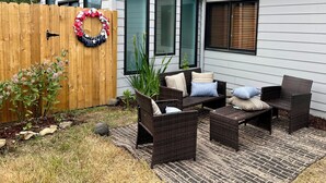 Une terrasse avec des meubles en osier, une clôture en bois et une guirlande décorative.