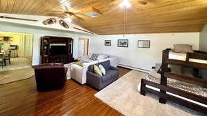 Une pièce chaleureuse avec un plafond en bois, un ventilateur de plafond, un canapé, une petite table et un lit superposé.