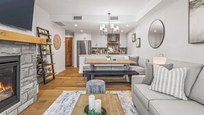 Una sala de estar moderna con chimenea, un sofá, una mesa de centro y un comedor con un banco.