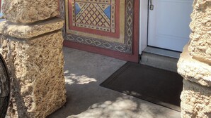 Una entrada de piedra con una reja metálica decorativa y una puerta blanca.