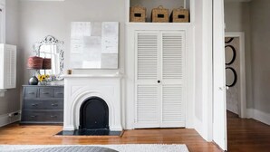 Une chambre avec une cheminée, une commode, un miroir et un ensemble de volets blancs.