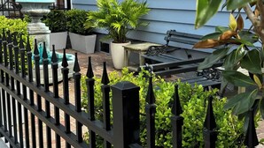 Un espace extérieur clos, agrémenté d’un banc, de plantes en pot et d’une fontaine.