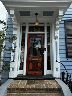 A front door with a number "163" above it, a wooden door with glass panels, and a small porch with steps leading up to it.